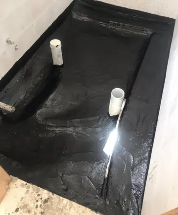 سطح مغطى بطبقة عزل سوداء وتظهر عليه أنبوبان أبيضان